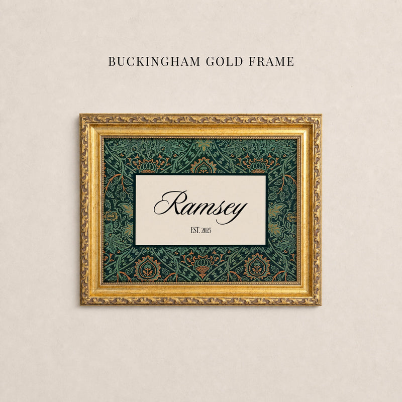 May include: A rectangular gold frame with ornate detailing surrounding a central cream-colored rectangular insert. The insert features a dark green and orange floral pattern border with the text Ramsey and EST. 2025 in black script and serif font.