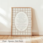 a framed print with a religious text, specifically a prayer or Bible verse, displayed on a wooden floor against a white wall.