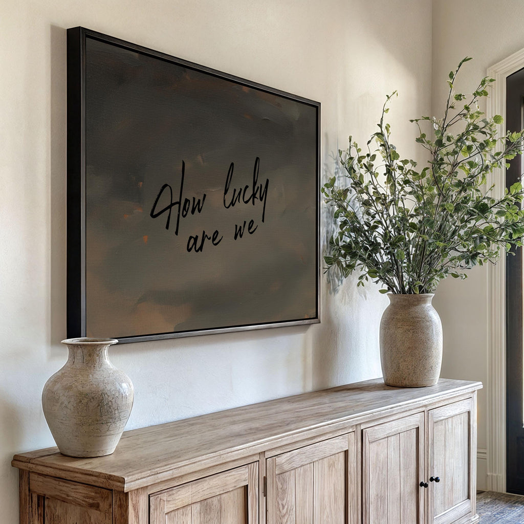 a wooden cabinet with a large framed picture hanging on the wall above it, and two vases placed on the cabinet.