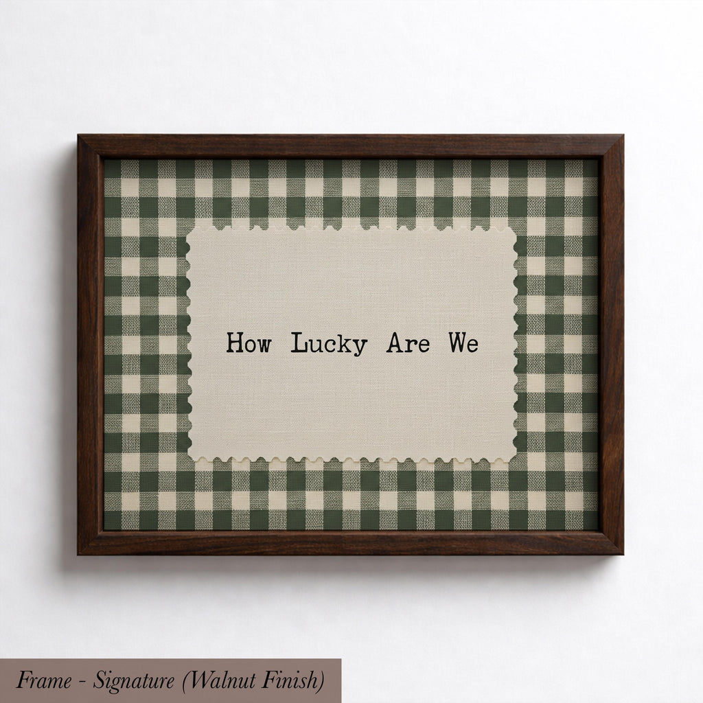 A framed picture with a checkered fabric border and a piece of paper with the text "How Lucky Are We" on it.