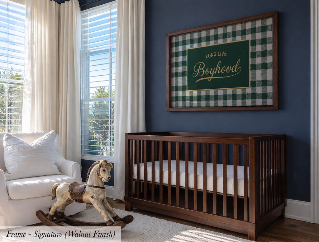 a nursery room with a wooden crib, a rocking chair, and a framed sign with the text "Long Live Boyhood" on the wall.