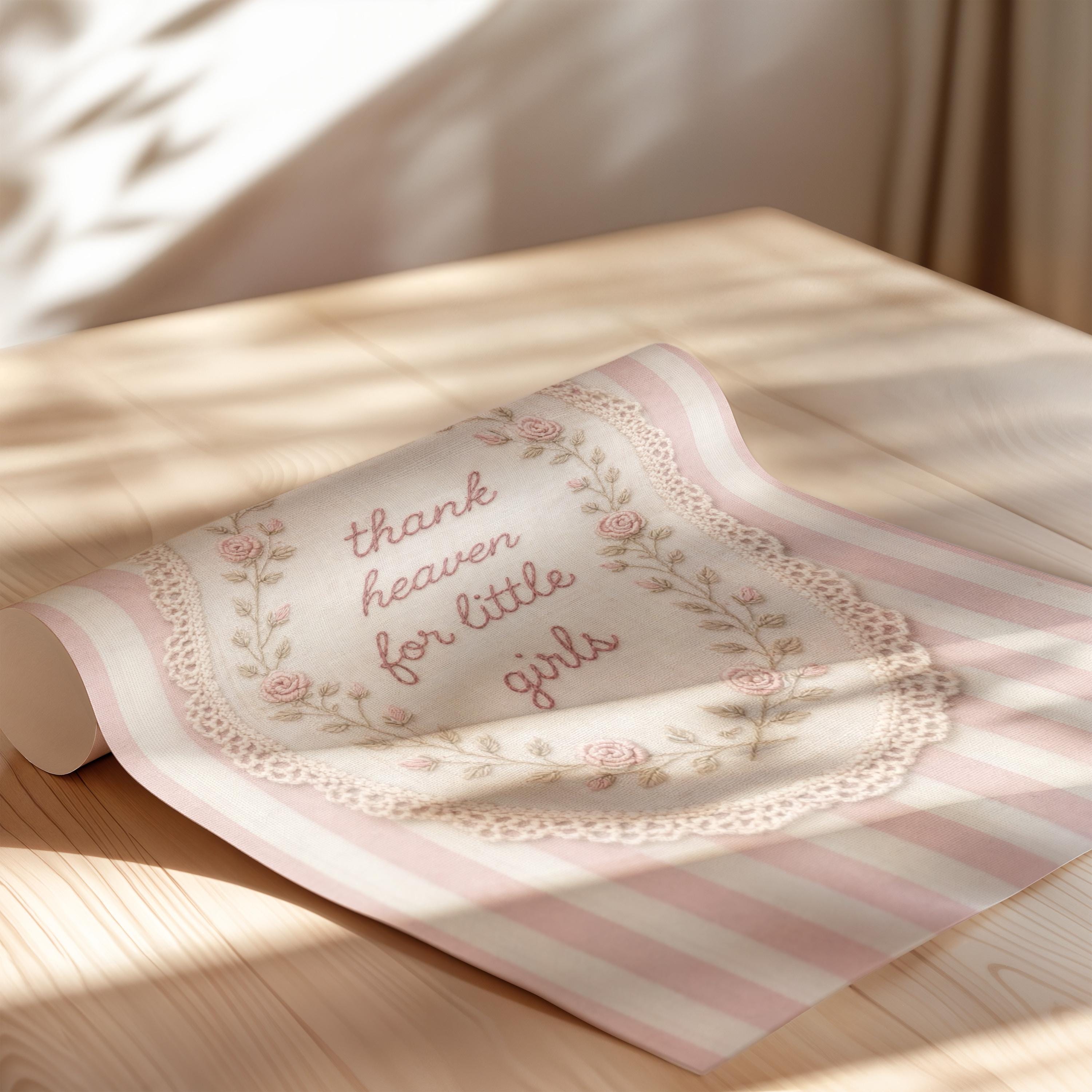 a decorative fabric with a floral pattern and the text "Thank heavens for little girls" printed on it, placed on a wooden surface.
