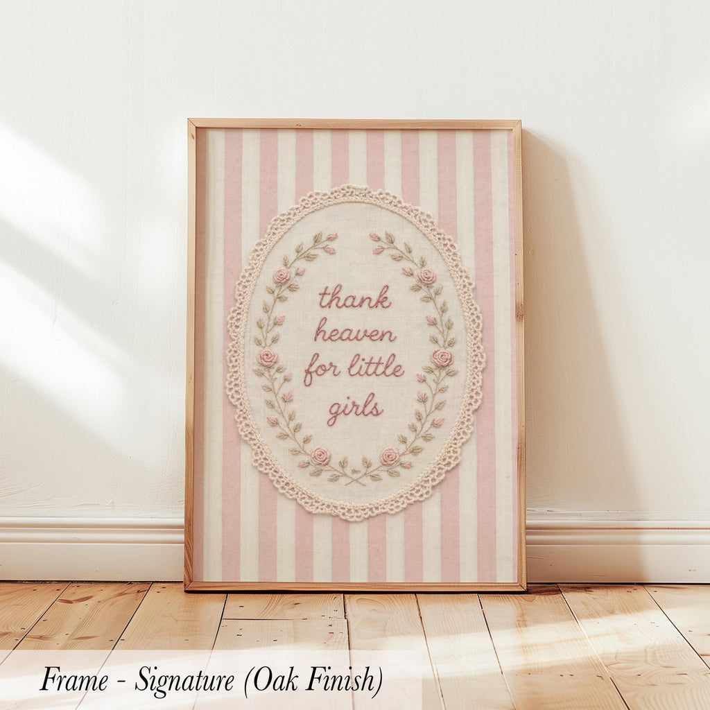 A framed print with a pink and white striped background and a lace border, featuring the text "Thank heaven for little girls" in a decorative font.