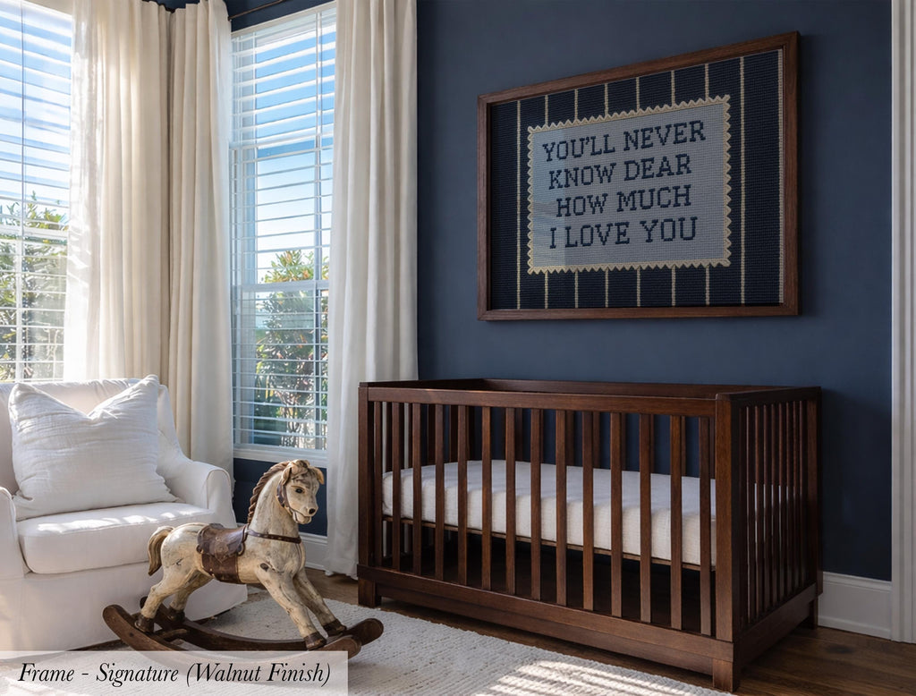 A nursery room with a wooden crib, a rocking horse, and a framed sign with a message. The room has blue walls and large windows that let in natural light.