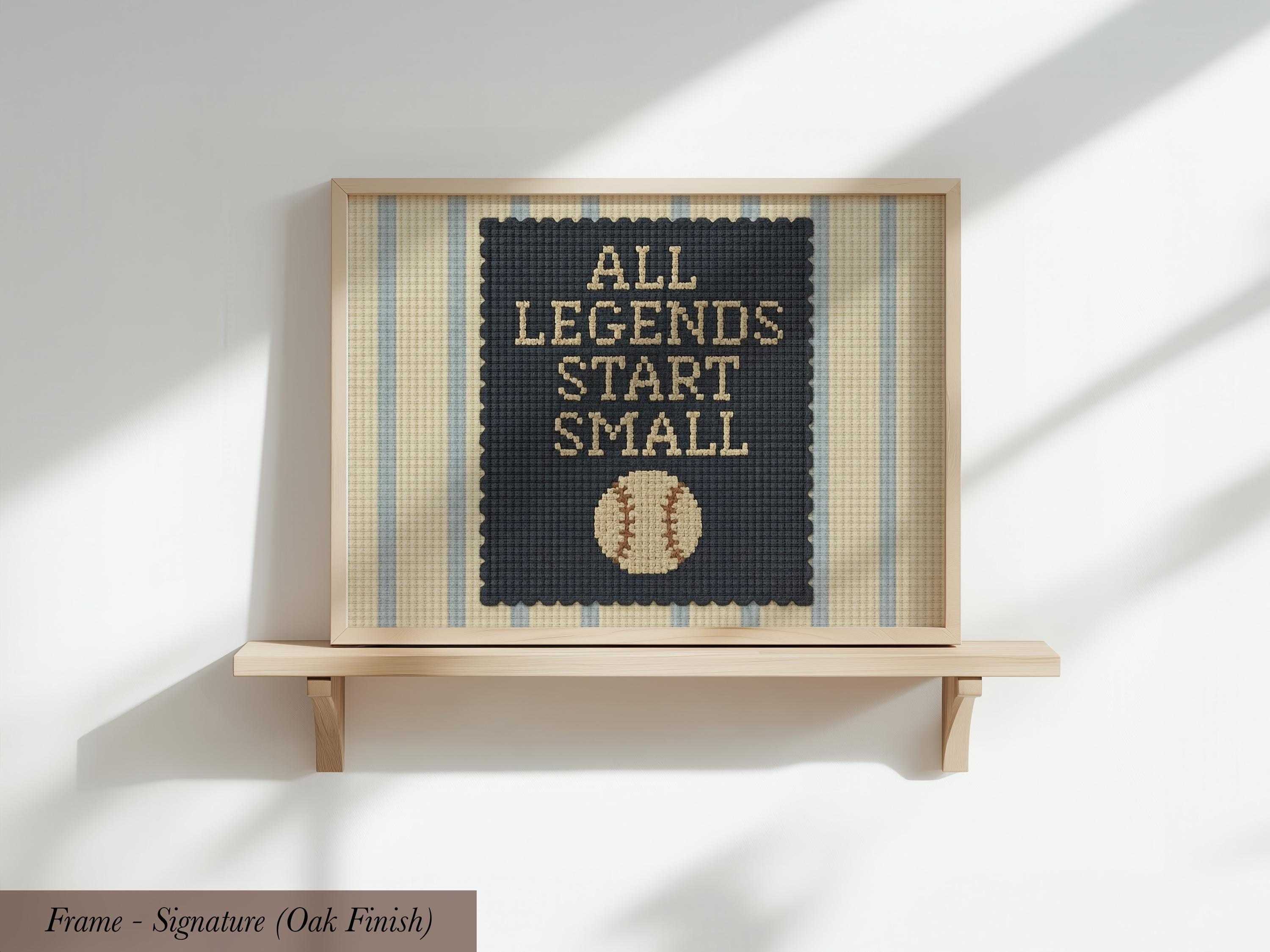 A framed poster with the text "ALL LEGENDS START SMALL" and a baseball graphic on it, displayed on a wooden shelf against a white wall.