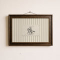 a framed picture of a cowboy riding a horse, with a small piece of paper with a drawing of a cowboy and a horse in the center of the frame.