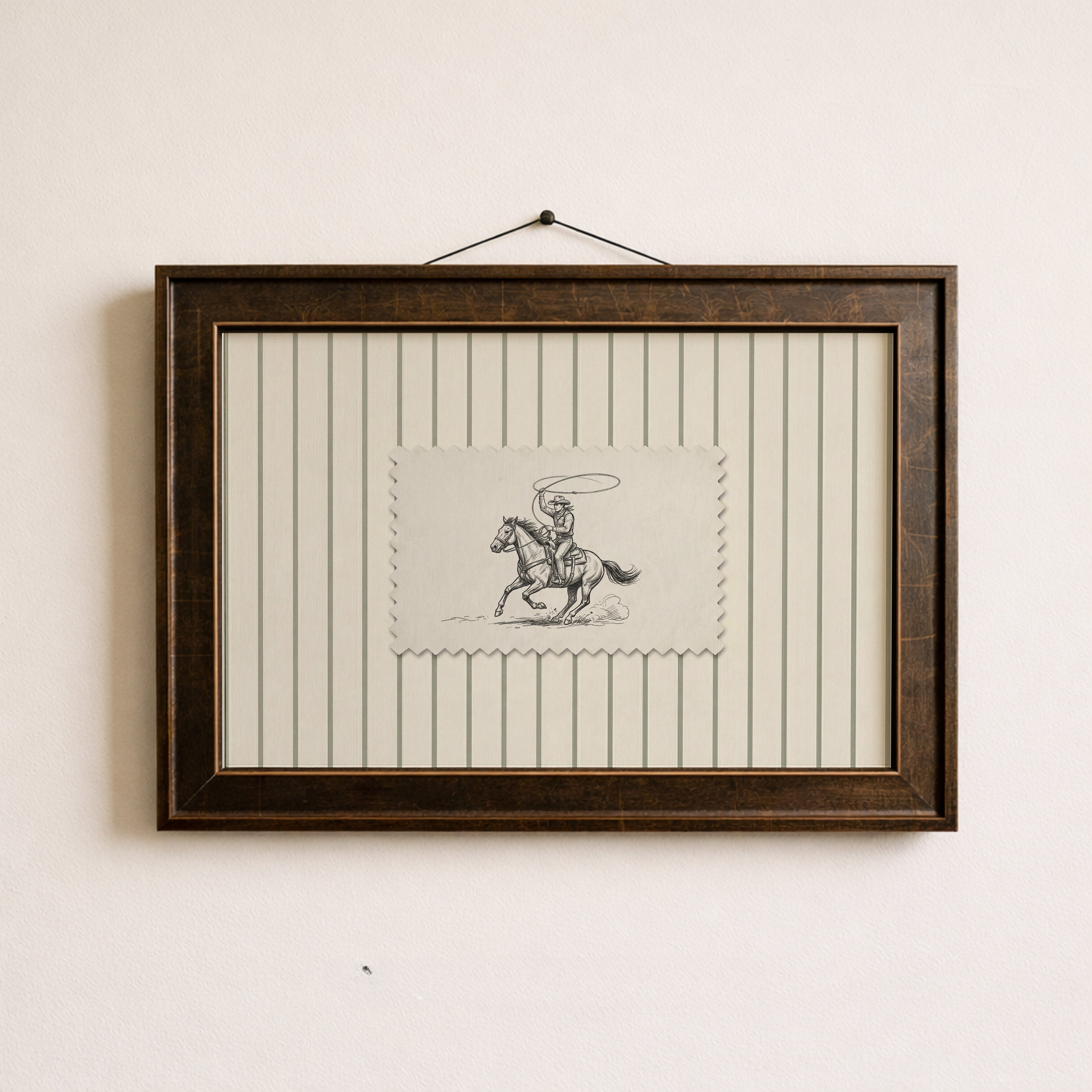 a framed picture of a cowboy riding a horse, with a small piece of paper with a drawing of a cowboy and a horse in the center of the frame.