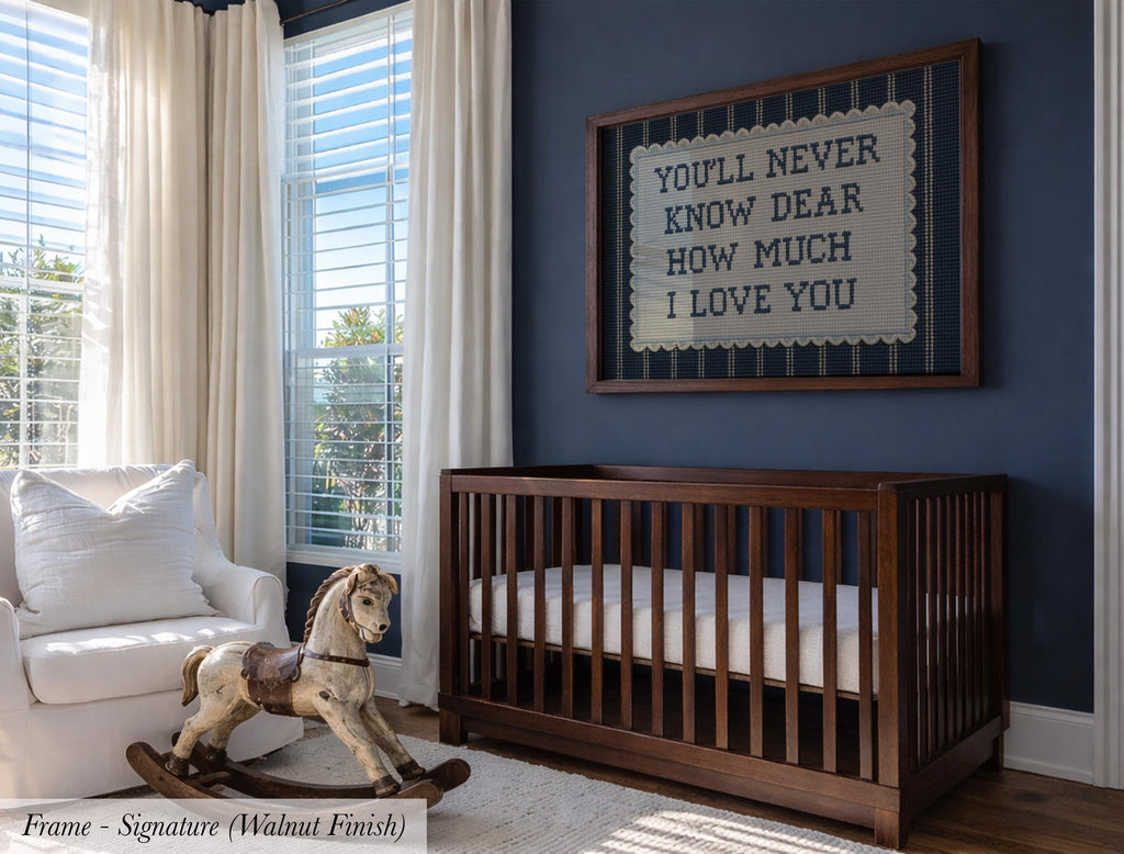A nursery room with a wooden crib, a rocking horse, and a framed sign with a message. The room has blue walls and large windows that let in natural light.