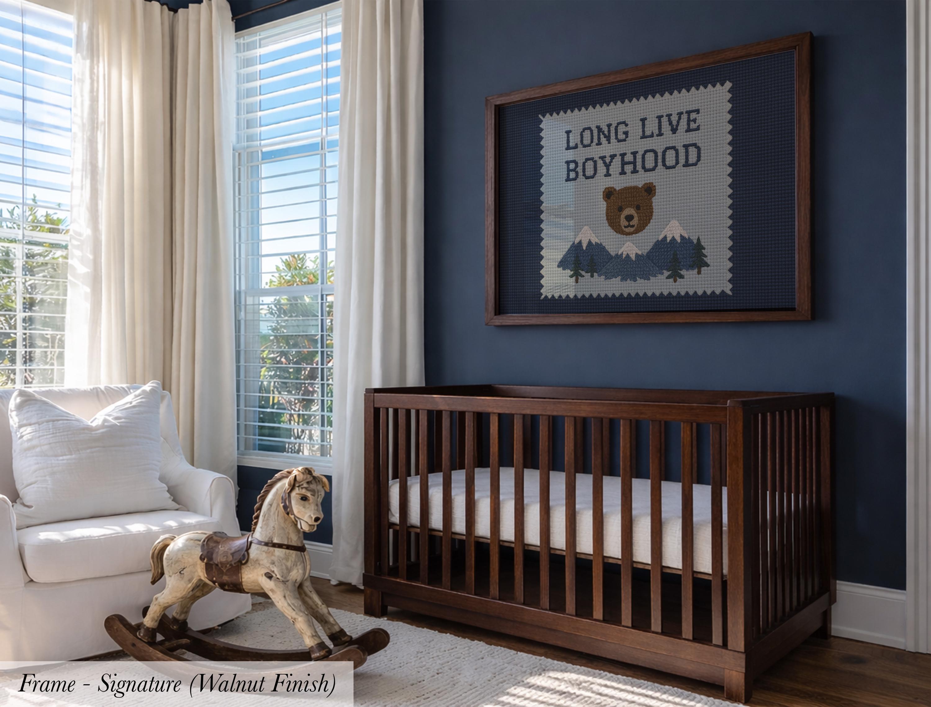 A wooden crib with a rocking horse sits in a nursery, with a framed poster above it that reads "LONG LIVE BOYHOOD".