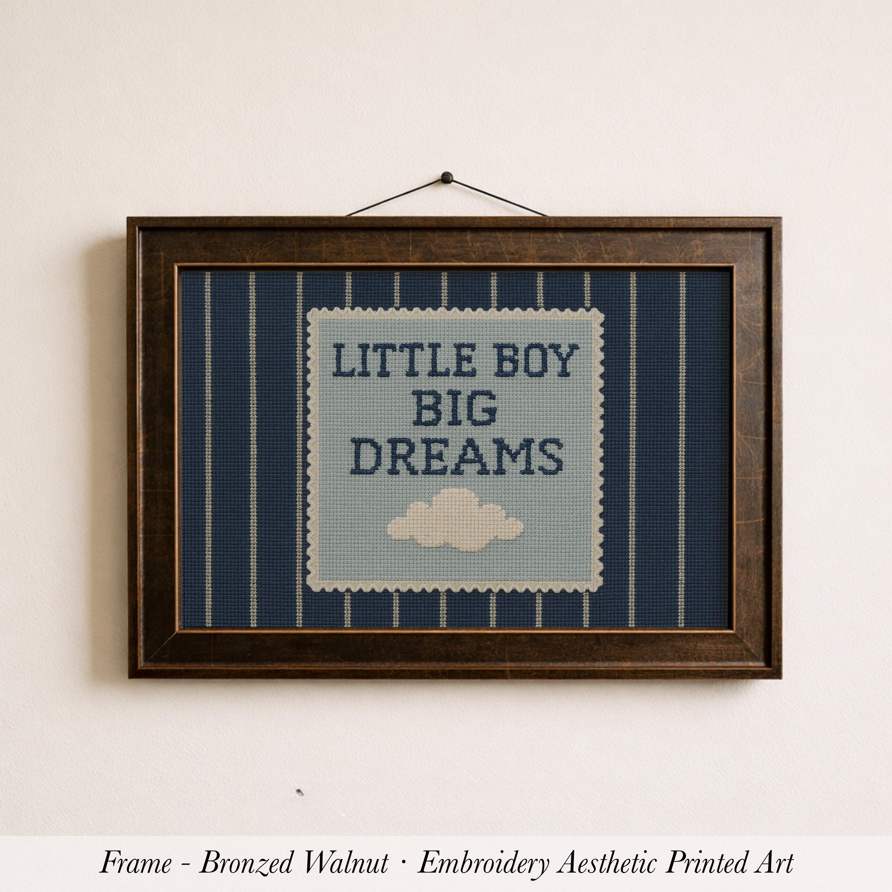 A framed embroidered art piece with the text "LITTLE BOY BIG DREAMS" on it, hanging on a wall.