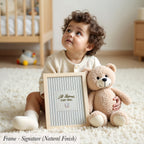 A young child sits on the floor, holding a framed sign that says "All Legends Start Small". Next to the child is a teddy bear.