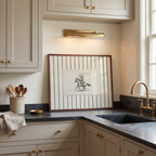 a kitchen with a framed picture of a cowboy on the wall above a sink. The kitchen has white cabinets and a marble countertop.