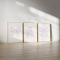 three framed pictures of bows on a wall, with the middle picture having a large bow and the other two having smaller bows.