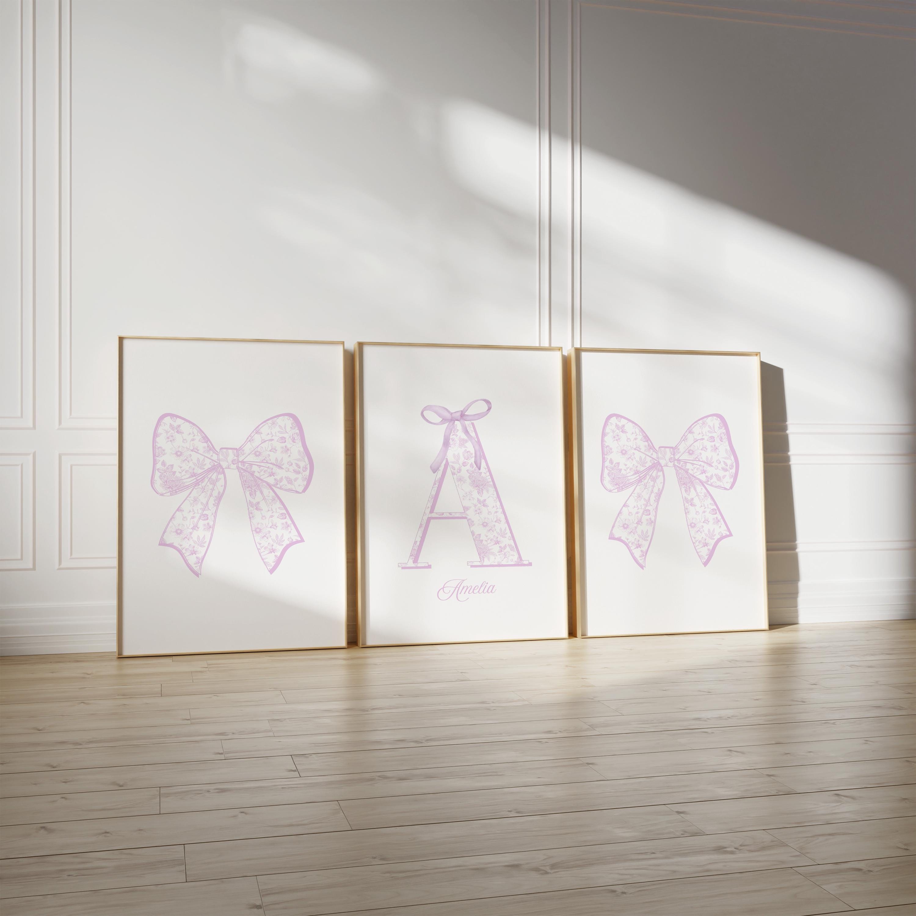 three framed pictures of bows on a wall, with the middle picture having a large bow and the other two having smaller bows.