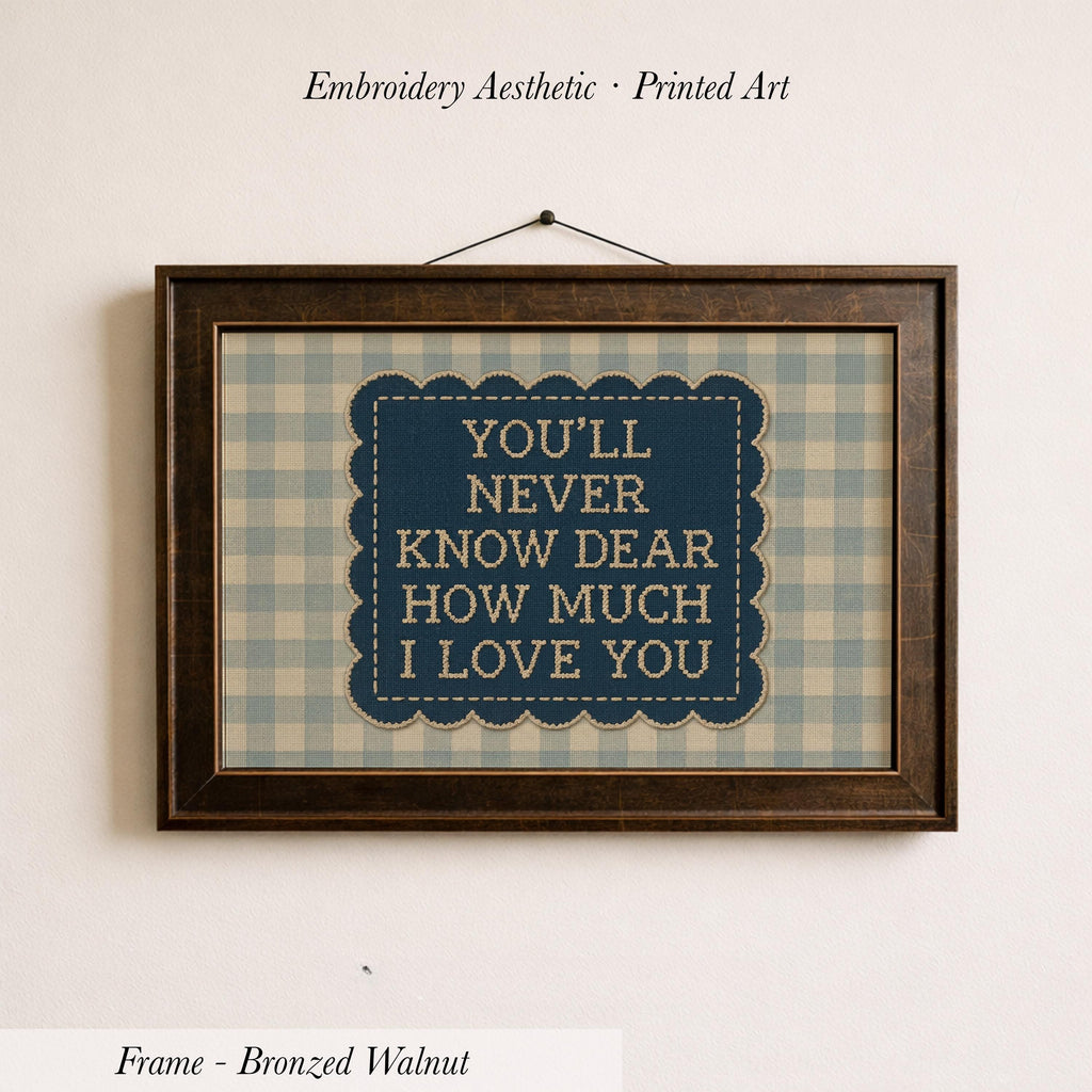 a framed print with the text "YOU'LL NEVER KNOW DEAR HOW MUCH I LOVE YOU" displayed on it.