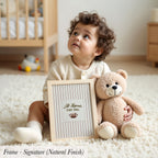 A young child sits on the floor, holding a framed sign that says "All Legends Start Small". Next to the child is a teddy bear.