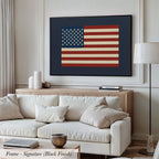 a living room with a large framed picture of the American flag hanging on the wall above a white sofa.