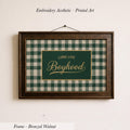 a framed piece of embroidered printed art with a green and white checkered pattern. The text on the frame reads "LONG LIVE BOYHOOD".