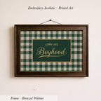 a framed piece of embroidered printed art with a green and white checkered pattern. The text on the frame reads "LONG LIVE BOYHOOD".
