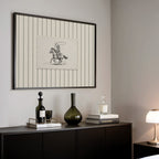 a black and white framed picture of a cowboy on a horse, a black vase, a stack of books, and a lamp on a black dresser.