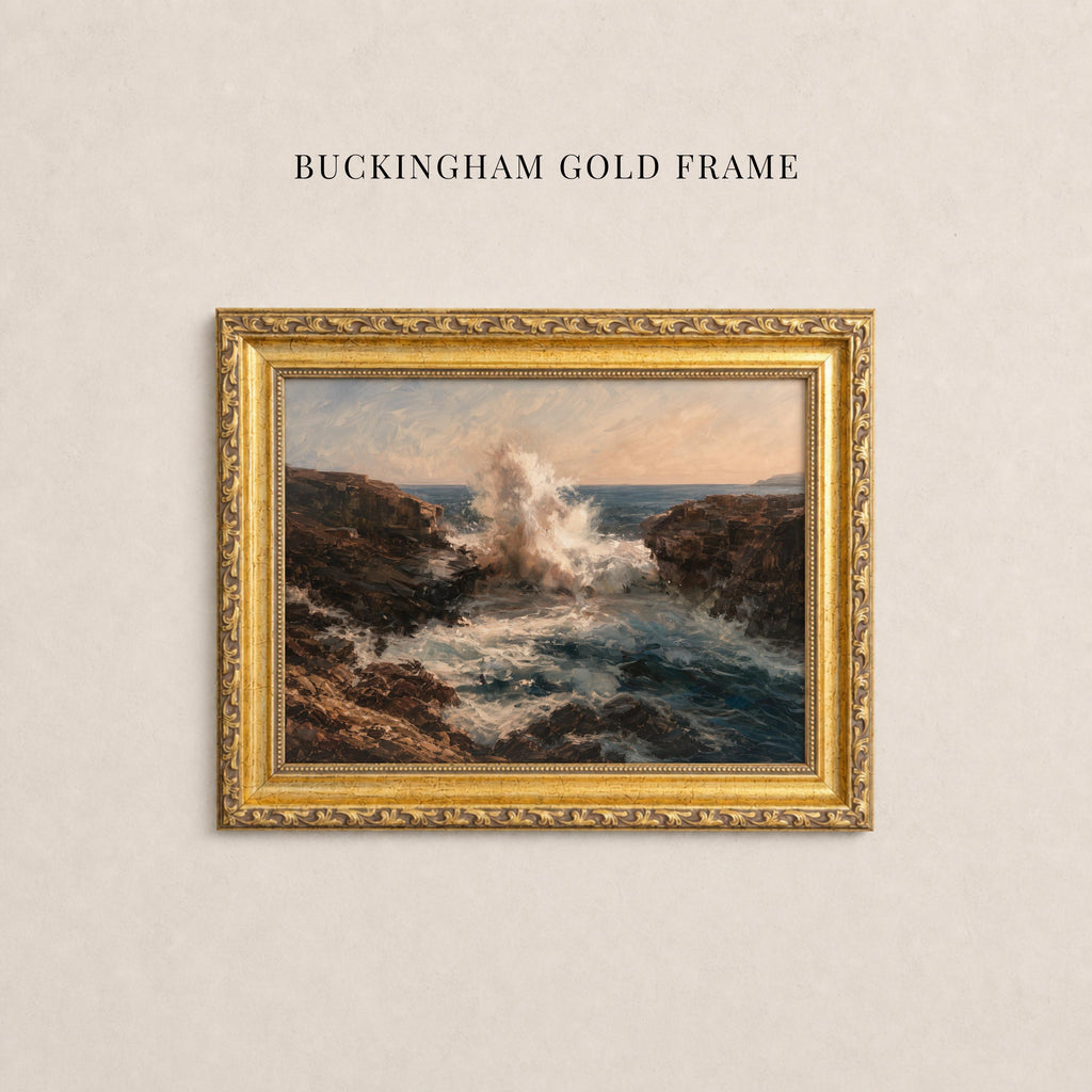 A painting of a rocky coastline with crashing waves is displayed in a gold-framed frame on a plain wall.