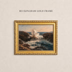 A painting of a rocky coastline with crashing waves is displayed in a gold-framed frame on a plain wall.