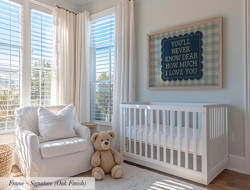 A cozy nursery with a white crib, a white chair, and a teddy bear. The room has large windows that let in natural light, and a framed sign with a message hangs on the wall.