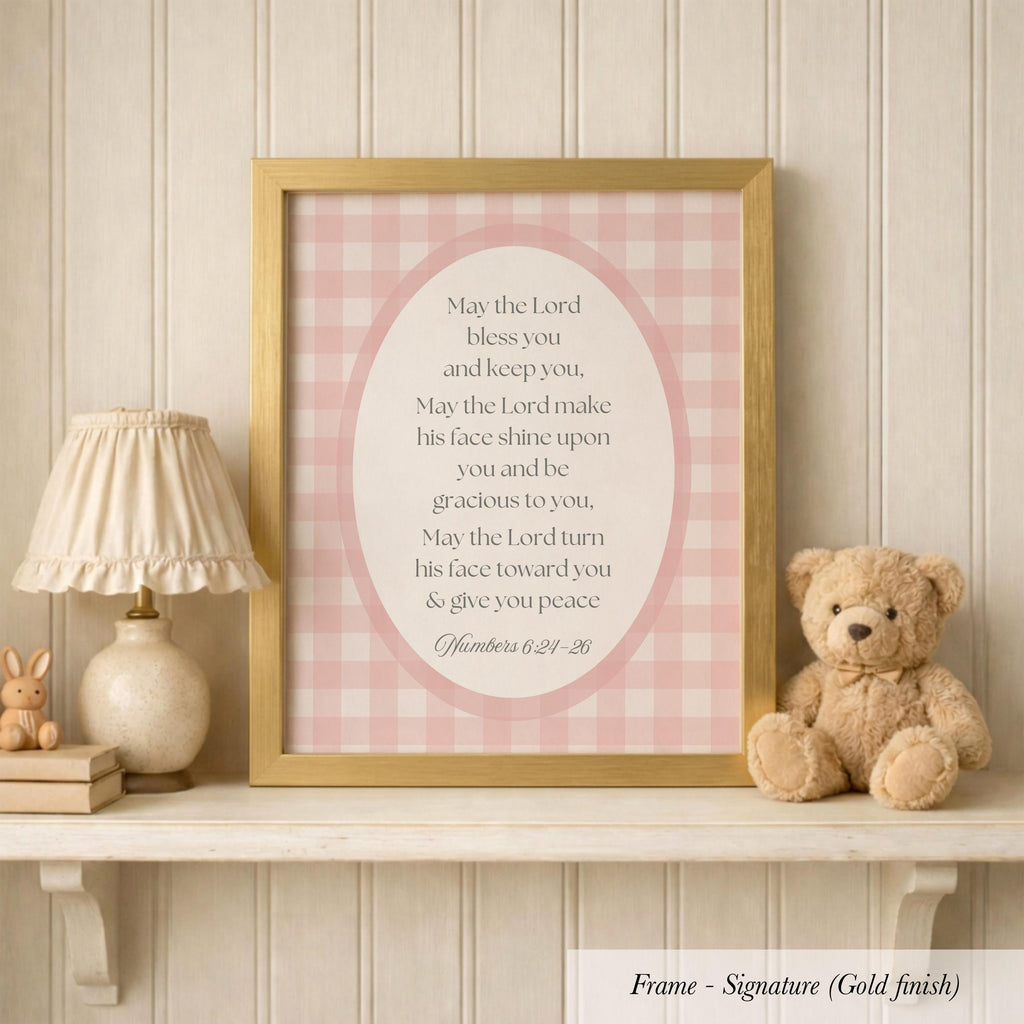 A framed Bible verse with a pink and white checkered background, accompanied by a teddy bear and a lamp on a shelf.