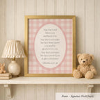 A framed Bible verse with a pink and white checkered background, accompanied by a teddy bear and a lamp on a shelf.