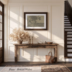 a rustic wooden console table with a vase of dried flowers, a picture frame, and a handbag, set against a white wall and a wooden staircase.