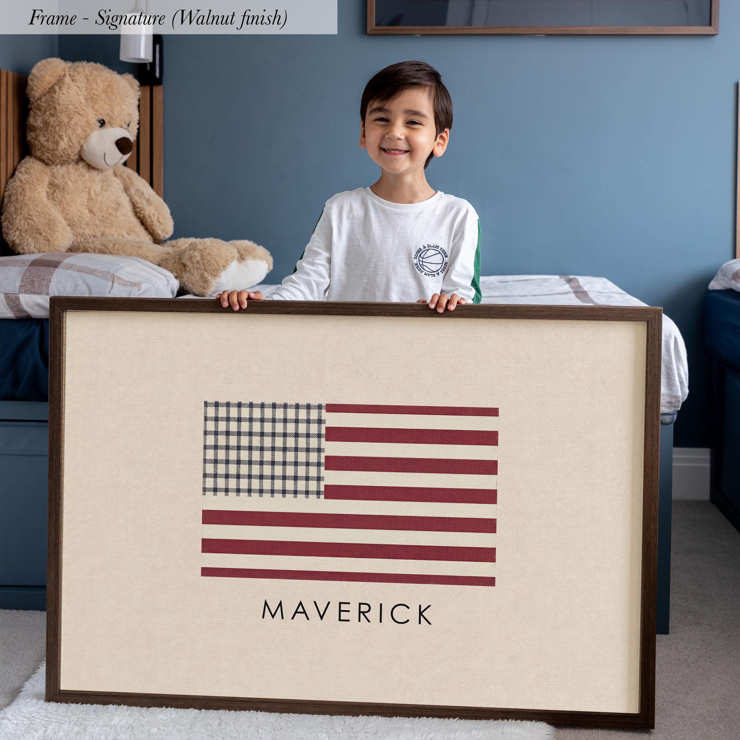A young boy is standing in a bedroom, holding a framed picture of the American flag.