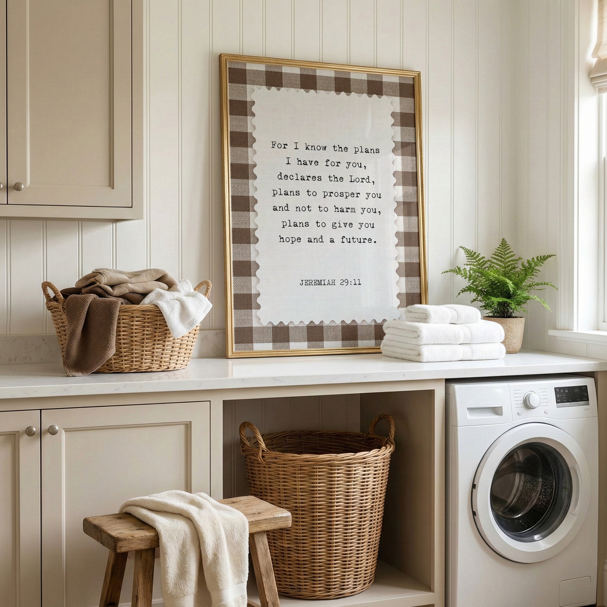a laundry room with a framed Bible verse, a washing machine, and a basket of towels.