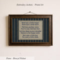 a framed piece of embroidered art with a printed poem on it, hanging on a wall.