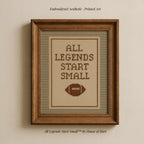 a framed embroidered cross-stitch design with the text "ALL LEGENDS START SMALL" and a football motif.