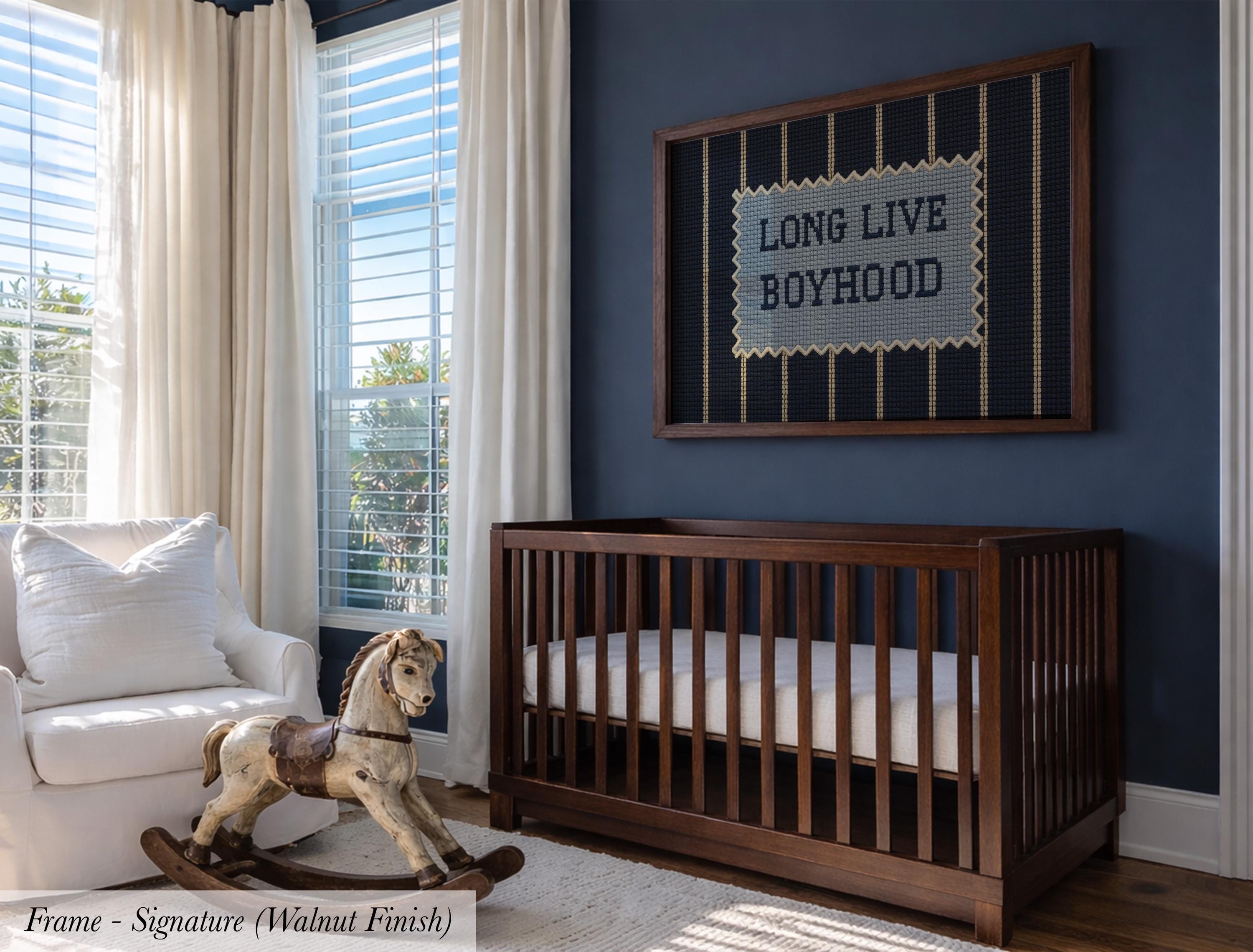 a nursery room with a wooden crib, a rocking chair, and a framed sign on the wall that reads "Long Live Boyhood".