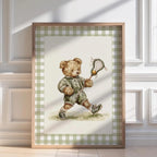 A framed watercolor painting of a teddy bear holding a lacrosse stick, wearing a green outfit and shoes, standing on a grassy surface.