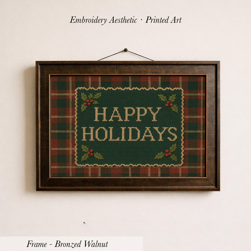 A framed embroidered design with the text "HAPPY HOLIDAYS" on a green plaid background, hanging on a wall.