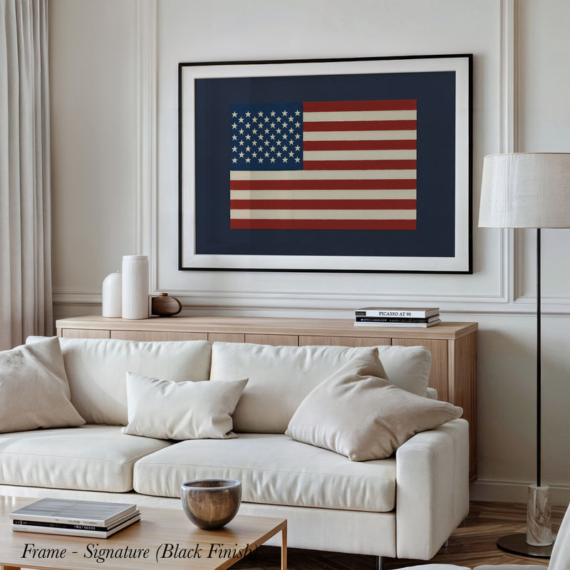 a living room with a large framed picture of the American flag hanging on the wall above a white sofa.