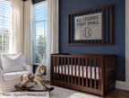 A nursery room with a wooden crib, a rocking horse, and a framed sign that says "All Legends Start Small".