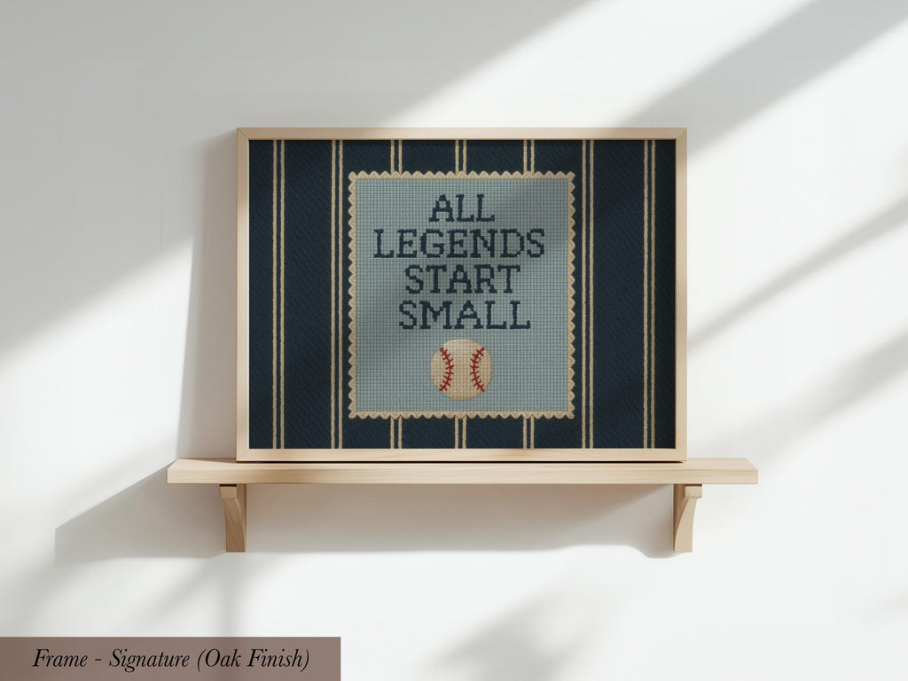 A framed cross-stitch design with the text "ALL LEGENDS START SMALL" and a baseball motif.