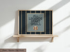 A framed cross-stitch design with the text "ALL LEGENDS START SMALL" and a baseball motif.