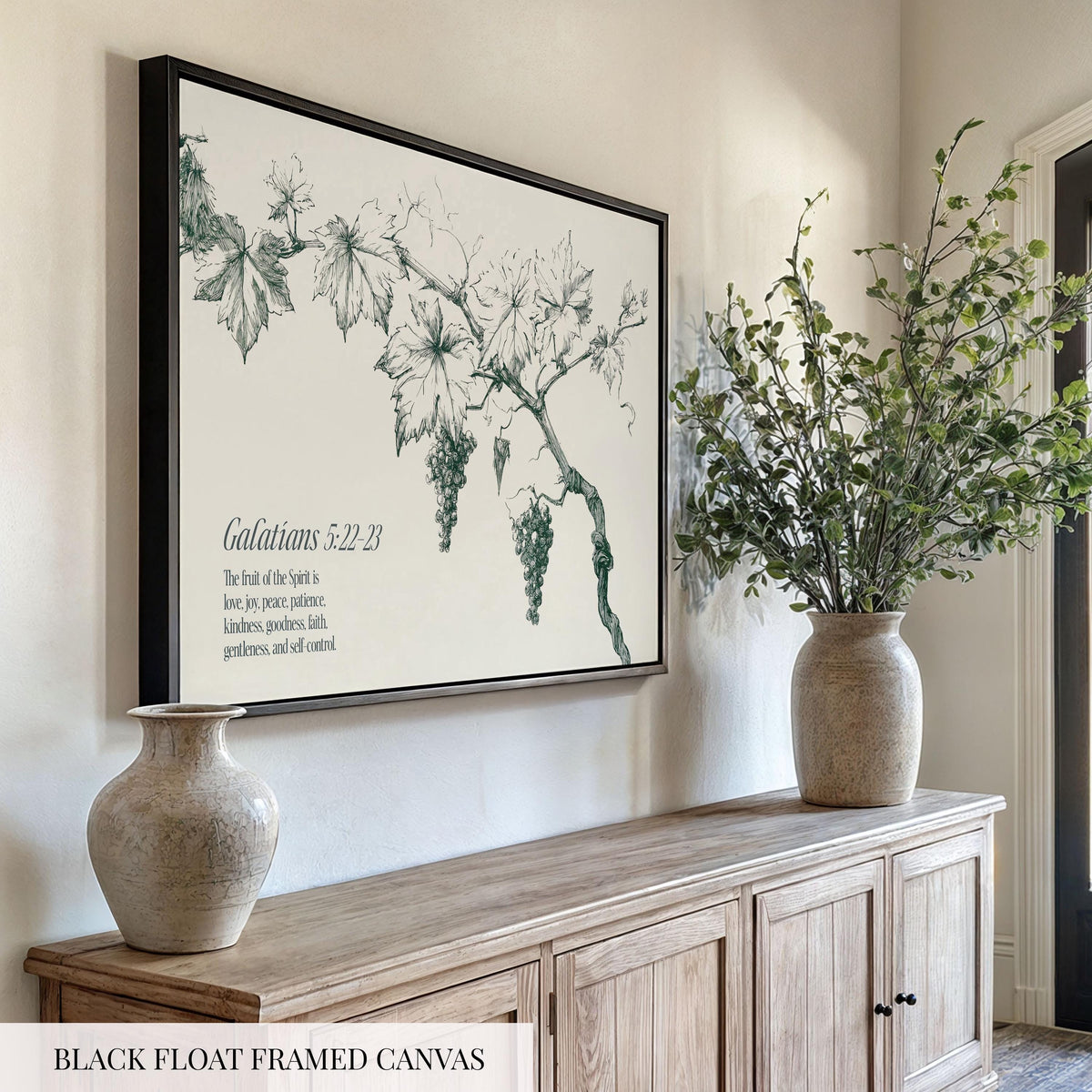 a black-framed canvas hanging on a wall, depicting a vine with grapes. Below the canvas, there are two vases on a wooden cabinet, and a potted plant on a shelf.