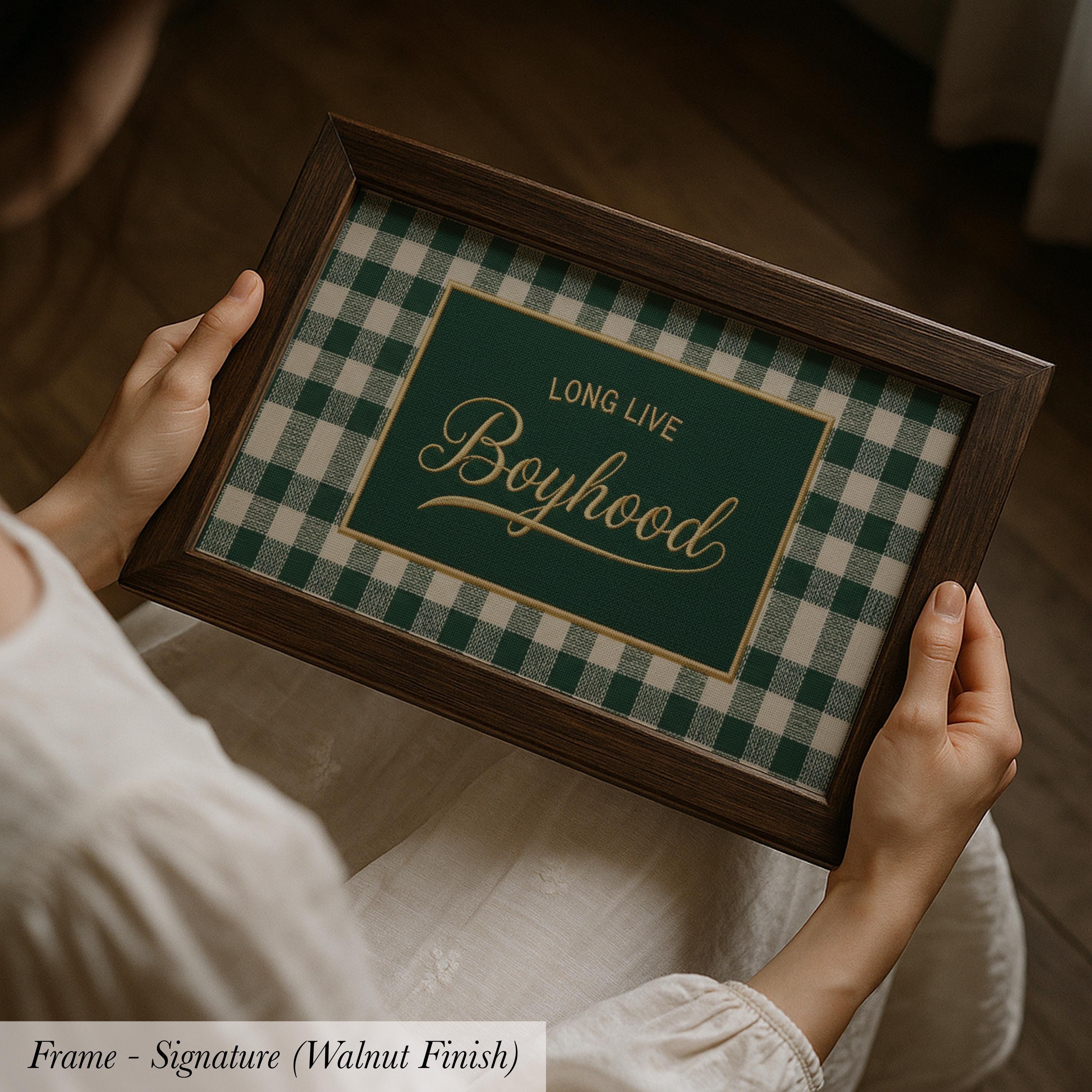 A person is holding a framed picture with the text "Long Live Boyhood" on it.