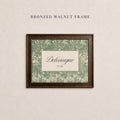 May include: A rectangular bronzed walnut frame containing a print with a green and cream botanical leaf pattern. The center features a cream rectangular inset with the text Delevingne and EST. 2004 printed in a dark serif font.