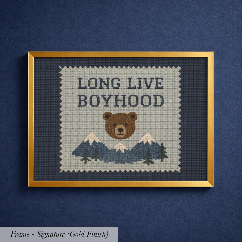 The image is a framed cross-stitch design featuring a bear and mountains, with the text "LONG LIVE BOYHOOD" displayed prominently.