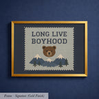 The image is a framed cross-stitch design featuring a bear and mountains, with the text "LONG LIVE BOYHOOD" displayed prominently.