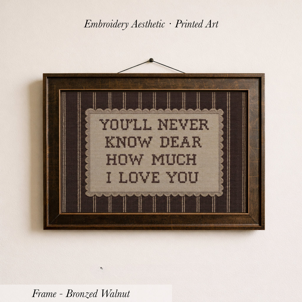 a framed embroidered piece of art with the text "YOU'LL NEVER KNOW DEAR HOW MUCH I LOVE YOU" on it.