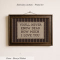 a framed embroidered piece of art with the text "YOU'LL NEVER KNOW DEAR HOW MUCH I LOVE YOU" on it.