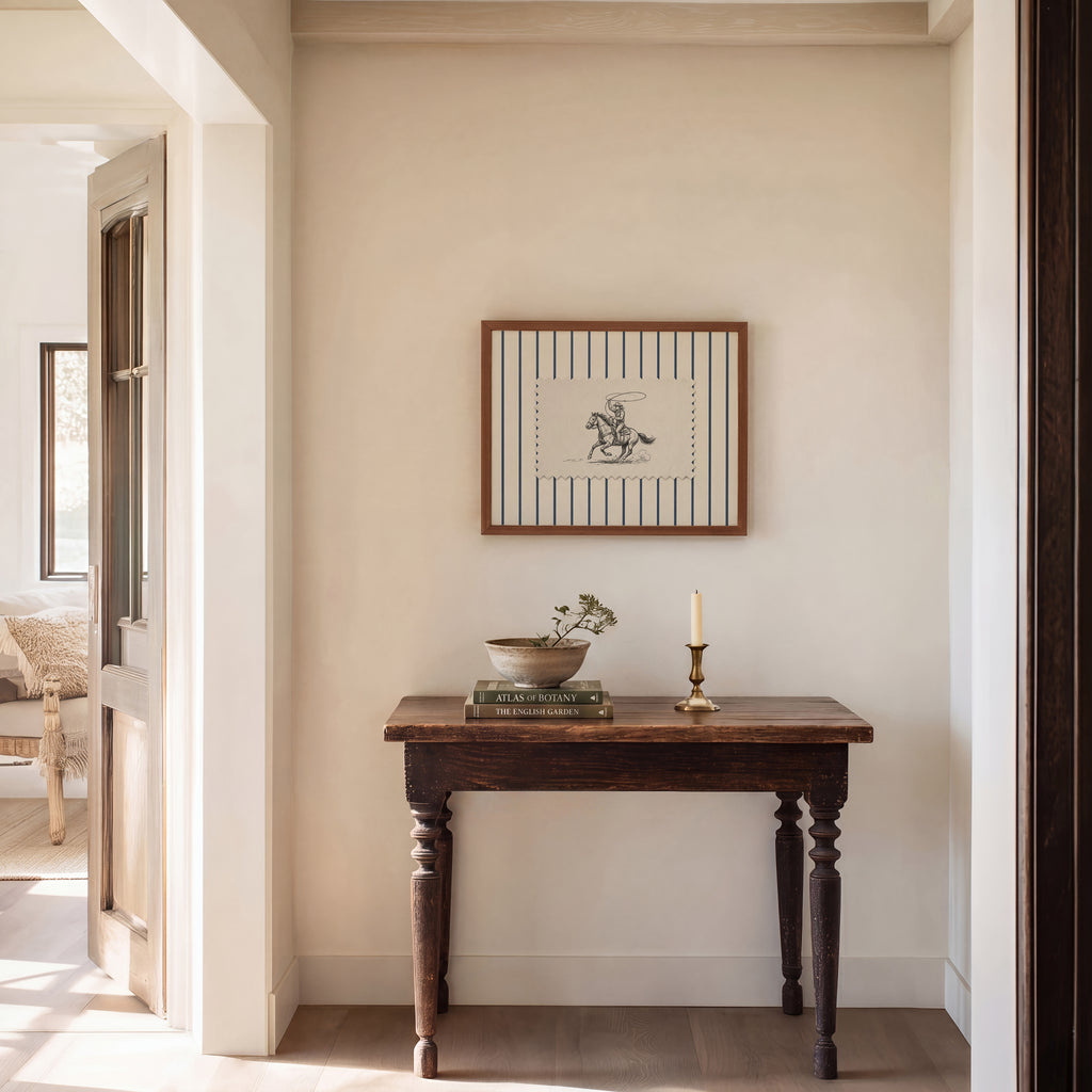 a cozy corner of a room with a wooden table, a framed picture, a candle, and a bowl of flowers.