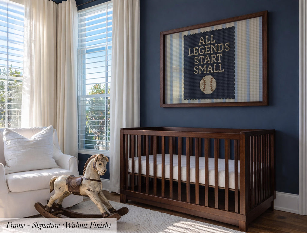 A nursery room with a wooden crib, a rocking chair, and a framed wall art with the text "ALL LEGENDS START SMALL".